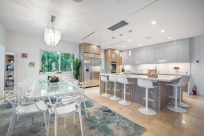A modern kitchen with a central island, bar stools, and a dining table with chairs.
