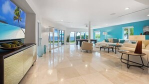 A spacious living area with a large TV, a dining table, and a sofa. - Bayfront Villa Heated Pool Amazing Views and Beach Access (North Bay Village)