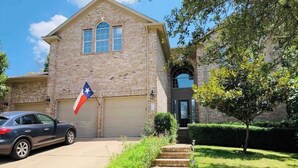 A two-story house with a brick exterior, a garage, and a flag. - Cheerful, Sunny☀️ Baller House in Round Rock (Round Rock)