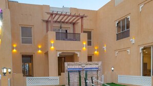 Un patio con piscina, una pequeña cascada y una pérgola.