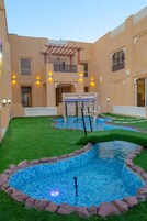 Un patio con piscina, una pequeña cascada y una pérgola.