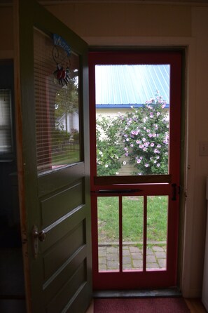A door with a decorative window and a hanging, set in a wall with an electrical outlet.