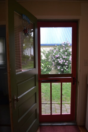 A door with a decorative window and a hanging, set in a wall with an electrical outlet.