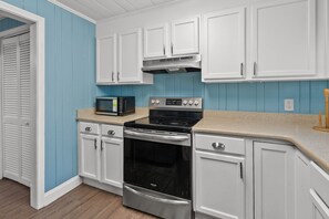 A kitchen with white cabinets, a black stove, and a microwave.