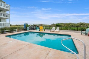 A swimming pool with a clear blue water, surrounded by a fence, and several lounge chairs. - Space for the whole family! 9-bedroom oceanfront home w/fantastic pool & deck in North Myrtle (North Myrtle Beach)