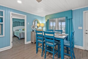 A room with a dining table, chairs, a bed, and a window with curtains. - Space for the whole family! 9-bedroom oceanfront home w/fantastic pool & deck in North Myrtle (North Myrtle Beach)