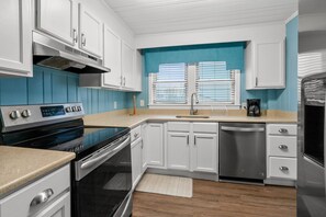 A modern kitchen with white cabinets, a stainless steel range, and a dishwasher.