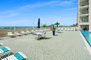 Een dakterras met een zwembad, ligbedden en parasols, en uitzicht op de oceaan.