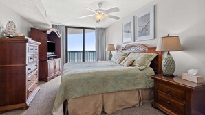 A hotel room with a bed, a dresser, a lamp, and a ceiling fan.