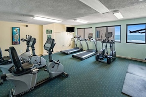 Een fitnessruimte met loopbanden, hometrainers en een roeimachine.