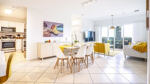 Una cocina moderna con comedor, una sala de estar con sofá y televisor, y un balcón con vistas.