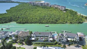 Un resort con varias edificaciones, un puerto deportivo y una isla verde exuberante.