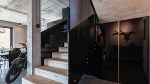 Un interior moderno con una escalera que conduce a una habitación oscura, una motocicleta y una decoración con cráneo de toro.