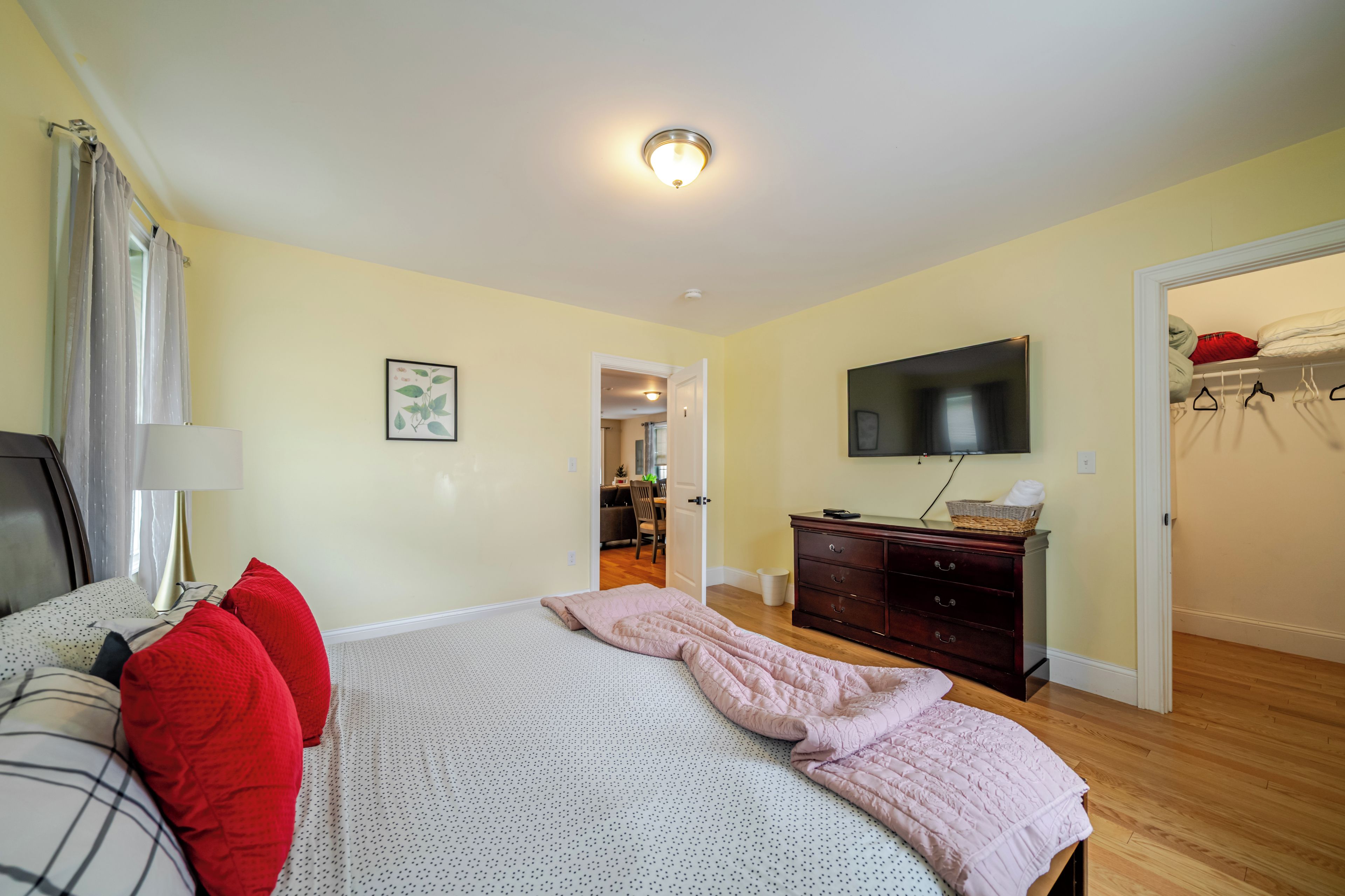 A bedroom with a bed, dresser, television, and a closet.