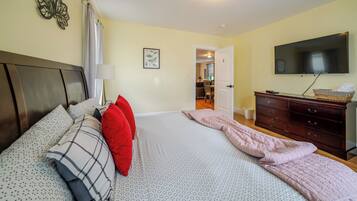 Un dormitorio con cama, cómoda, televisor y puerta que da a otra habitación.