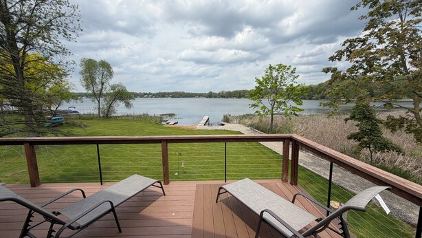 Une terrasse avec deux chaises longues donnant sur un lac.