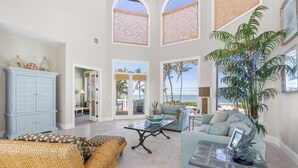 Un salon spacieux avec un plafond haut, de grandes fenêtres et une vue sur l’extérieur.
