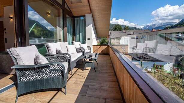 Un balcone con mobili in vimini e vista sulle montagne.