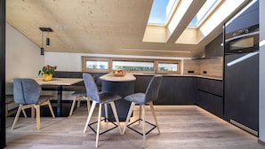 Una cucina moderna con lucernari, una zona pranzo con un tavolo rotondo e sedie, e una vista dalle finestre.