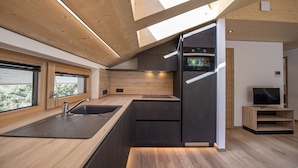 Una cucina moderna con forno integrato, lavello e televisore su un supporto in legno.