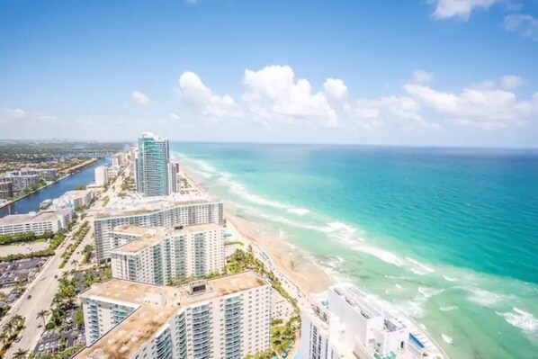 A coastal cityscape with high-rise buildings, a beach, and a marina.