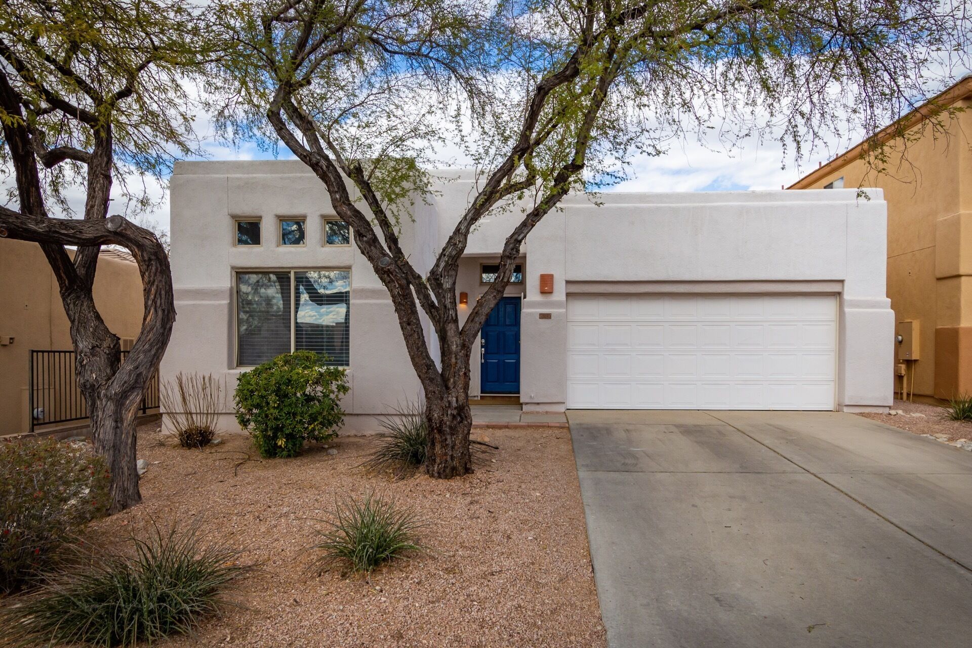 A modern two-story house with a garage, surrounded by desert landscaping.