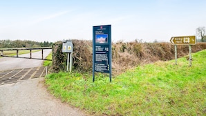 A directional sign for Kirby Hall, a historical building, with a warning sign nearby. - Contractor Accommodation - Cacco (Corby)