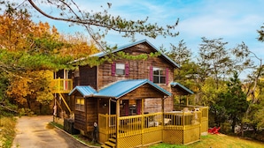 A wooden cabin with a porch and a covered deck, surrounded by trees. - Family‑Friendly Retreat: Hot Tub, Theater + Close to Attractions (Sevierville)