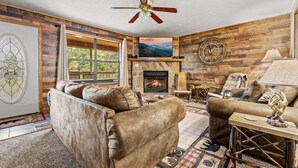 A cozy living room with a fireplace, leather sofas, a ceiling fan, and a large clock on the wall. - Family‑Friendly Retreat: Hot Tub, Theater + Close to Attractions (Sevierville)