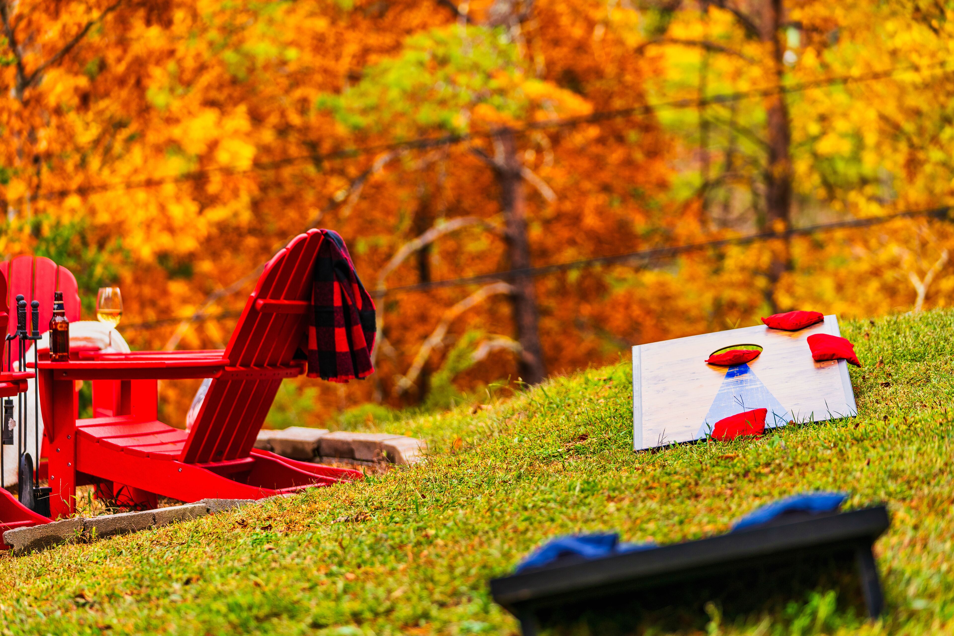 A red chair and table set on a grassy hill with autumn foliage in the background.