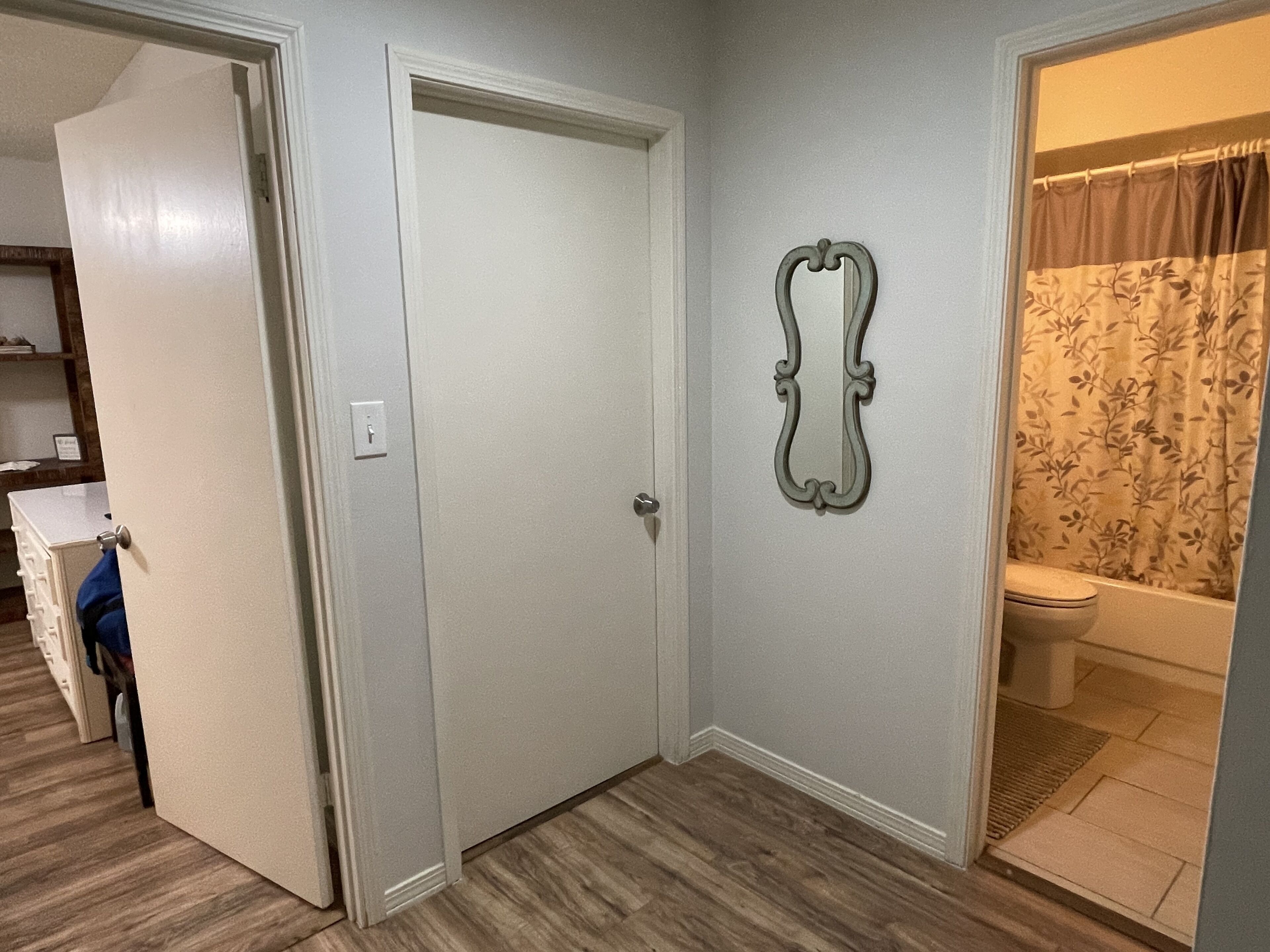 Un baño con inodoro, cortina de ducha y un espejo decorativo en la pared.