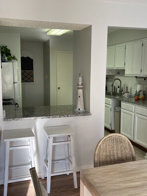 A kitchen with white cabinets, a granite countertop, and a white refrigerator.
