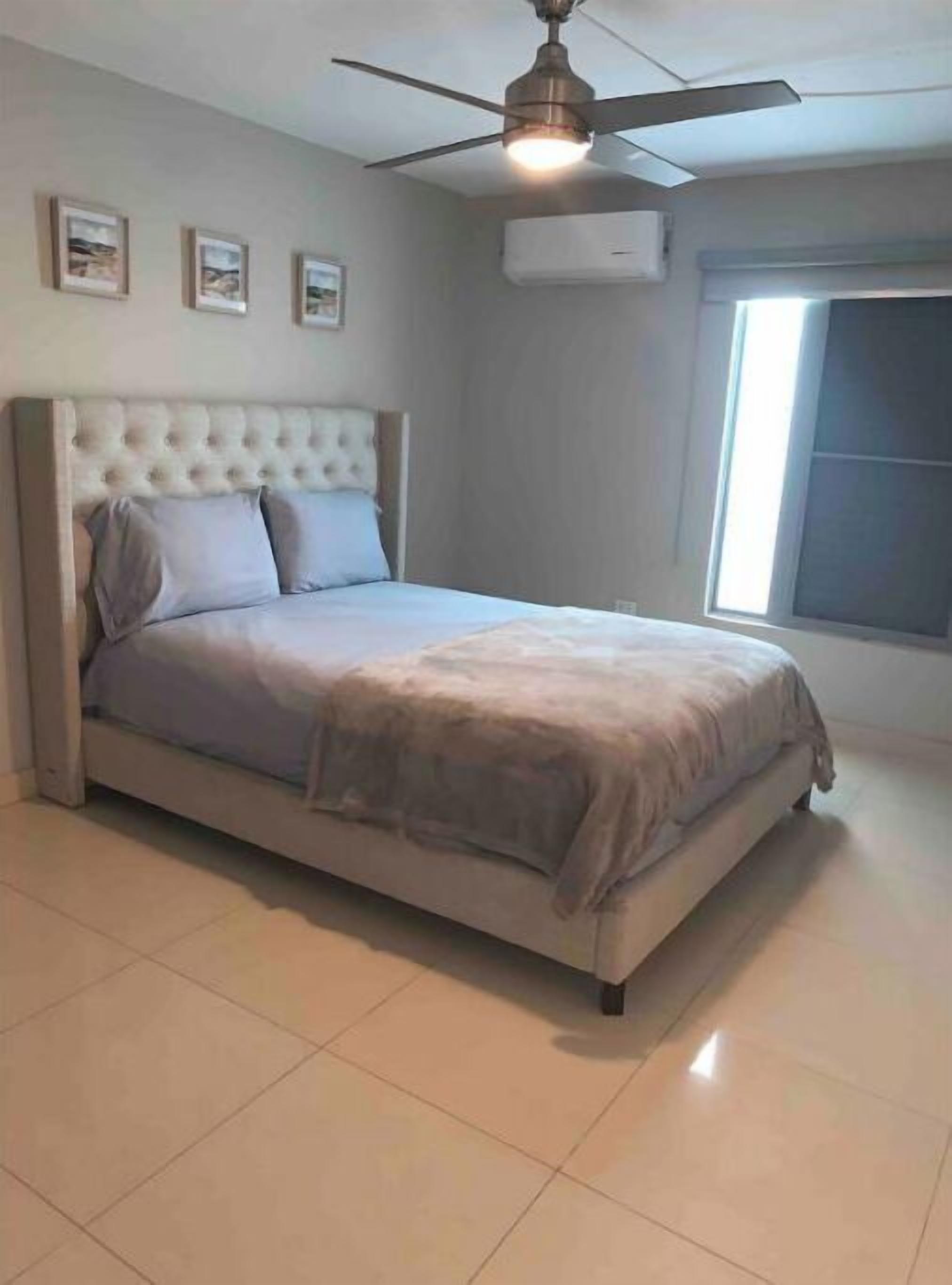 Un dormitorio con cama, ventilador de techo y ventana.