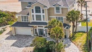 Una casa a due piani con un ampio portico, un garage e vista sull'oceano.