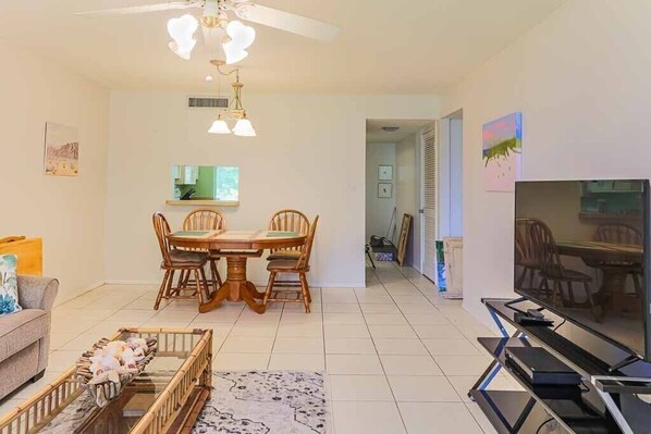 A living room with a dining table, chairs, a TV, and a ceiling fan. - Perfect stay, home away from home. (Caseville)