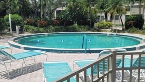 Une piscine avec des chaises longues et un espace délimité par une clôture.