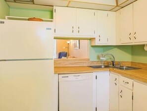 Efficient kitchen with a refrigerator, dishwasher, and sink, complete with gold hardware and a wooden countertop.