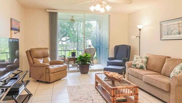 Un salon avec un canapé, deux fauteuils, une table basse et un téléviseur.