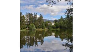 A tranquil lake surrounded by dense trees and a distant mountain range. - The Beeches Studio - Highlands of Scotland (Newtonmore)