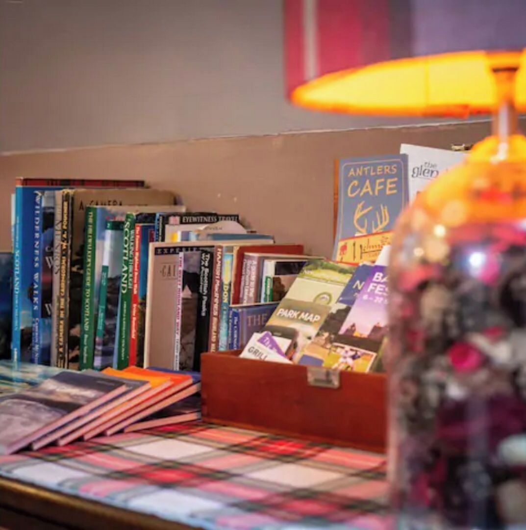 A book display with various titles, a lamp, and a sign for 'Antlers Cafe'.