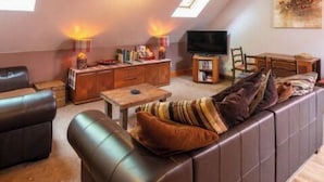 A cozy living room with a sofa, a coffee table, a TV, and a dining area. - The Beeches Studio - Highlands of Scotland (Newtonmore)