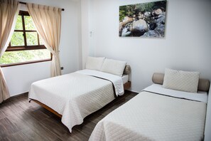 A room with two beds, a window with curtains, and a wall-mounted picture of a natural scene.