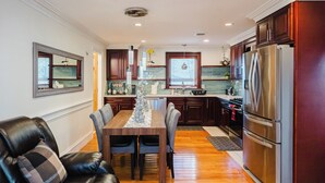 Una cocina moderna con armarios de madera oscura, un refrigerador de acero inoxidable y un comedor con mesa de madera y sillas de cuero.