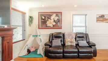 A living room with a brown leather sofa, a white tent, and a painting of flowers on the wall.