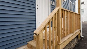 A wooden staircase leading to a white door with the number 39, flanked by siding and a small porch area. - Newly Built Greater Boston Townhouse Near I-93 • Parking • Pet-Friendly - 39 (Quincy)