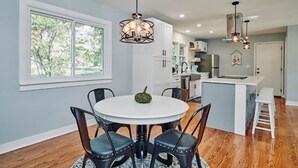 A modern kitchen with white cabinets, a central island, and pendant lighting. - Fox Valley Farmhouse by the river - walk to town & pool (St. Charles)