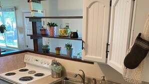 A compact kitchen with a stove, sink, and dishwasher. There are shelves above the sink holding various potted plants. - Adventurer's Paradise 🏔 ⛷ Close to Boulder/Denver (Lafayette)