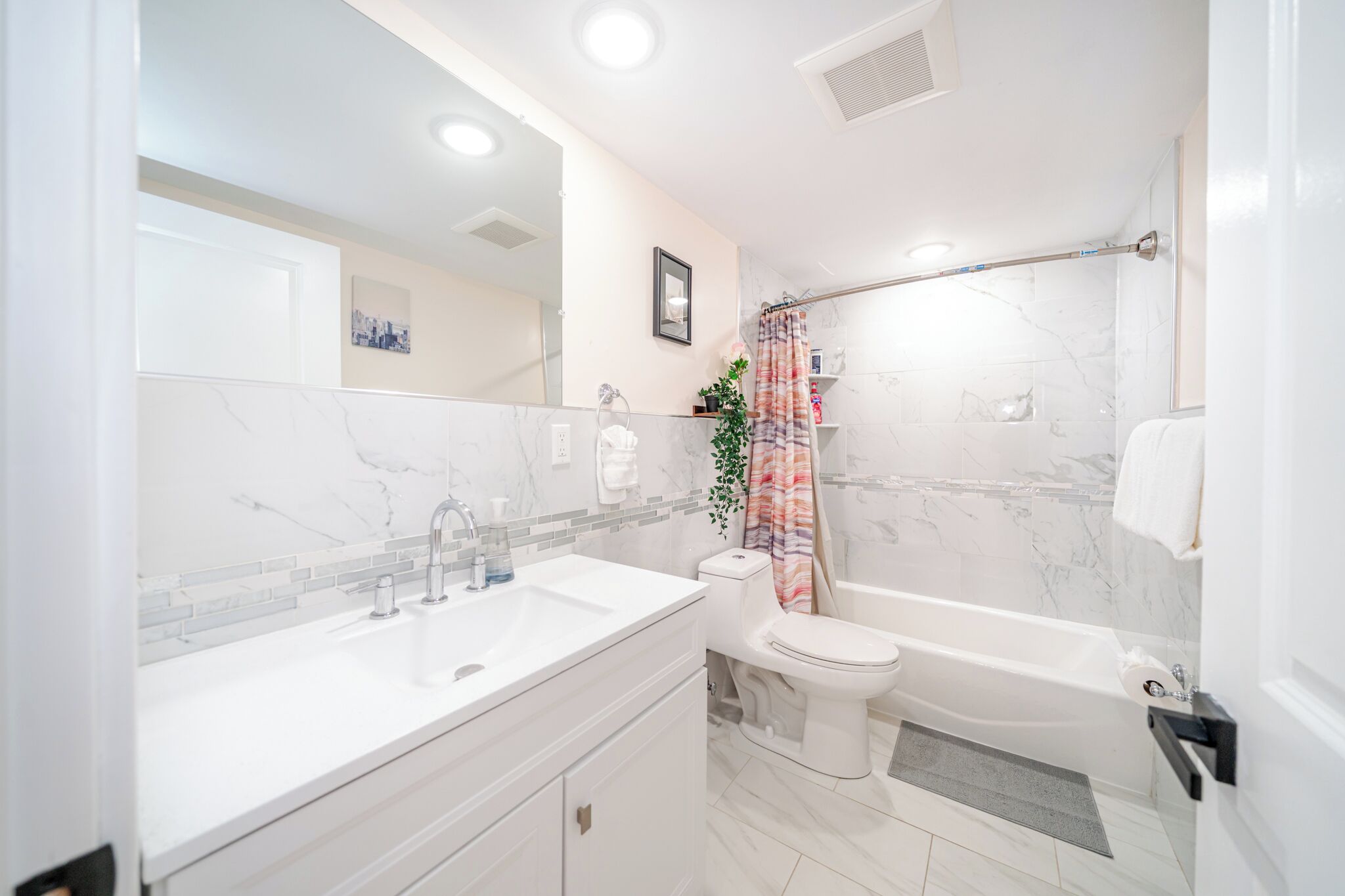 A modern bathroom with a white sink, toilet, and bathtub.