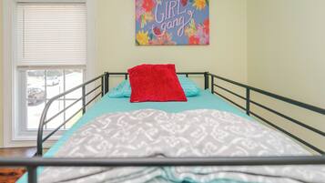 Cozy retreat with a single bed, patterned blanket, and vibrant artwork.