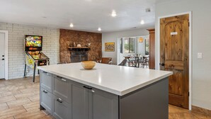 Une cuisine dotée d’un grand îlot central, d’un mur décoratif en pierre et d’une porte en bois.